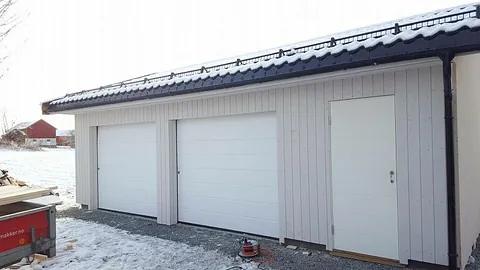 Ny garasje med tre porter og hvit kledning, snø på bakken