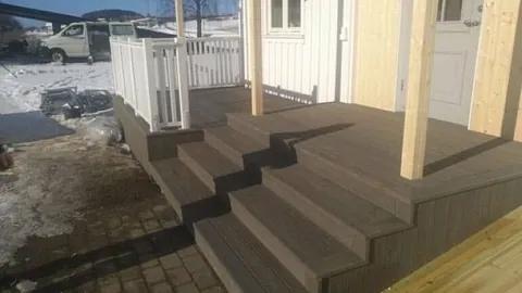 Ny trapp og terrasse i brun kompositt foran et hus